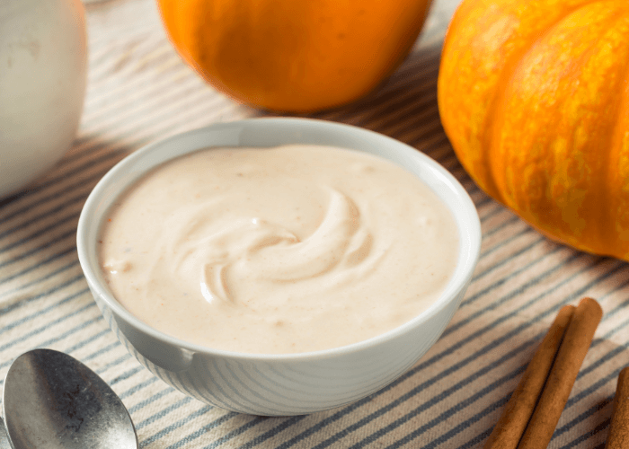 Pumpkin Yogurt Dip in a bowl with a pumpkin and cinnamon sticks