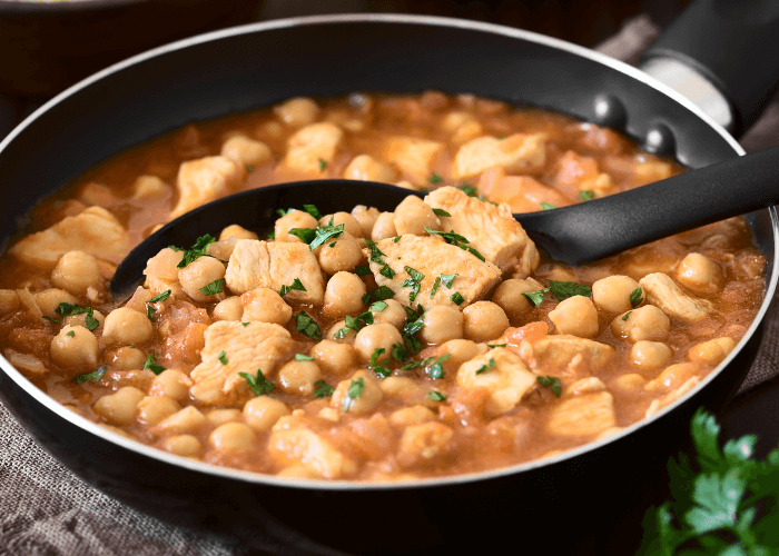 Black bowl with chicken soup and chickpeas.