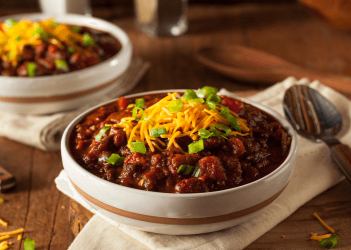 Turkey Chili in white bowl topped with cheese and green onions