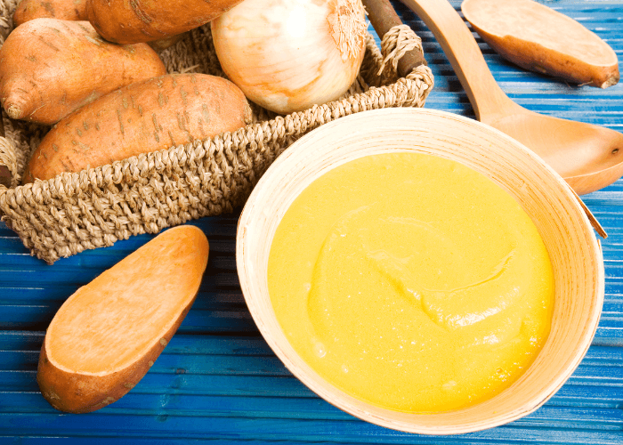 Sweet Potato Soup in a bowl with basket of sweet potatoes