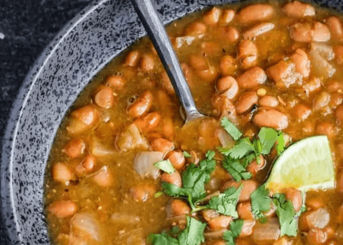 Salsa Pinto Beans in a bowl with chopped cilantro and lime