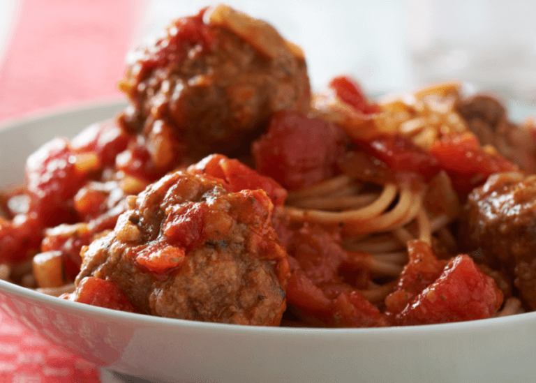 Spaghetti and meatballs in a white bowl.