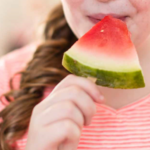 Child with a watermelon slice on a popsicle stick