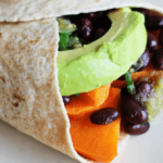 Closeup photo of a sweet potato and black burrito on a white surface