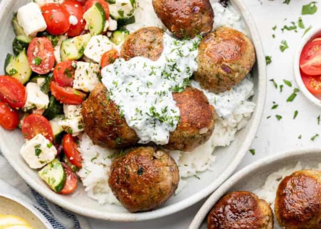 Greek Turkey Meatballs with Tzatziki, cucumbers, tomatoes, feta in a white bowl