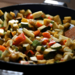 Vegetable stir fry in a cast iron pan with zucchini, squash, peppers