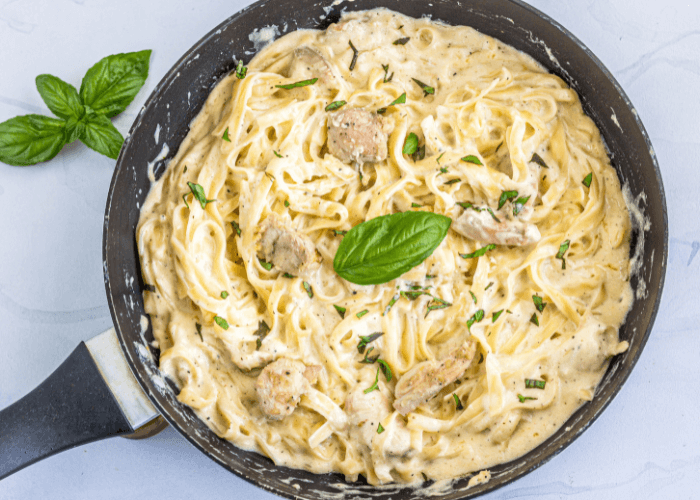 One-Pot Chicken Alfredo in a skillet with fresh basil