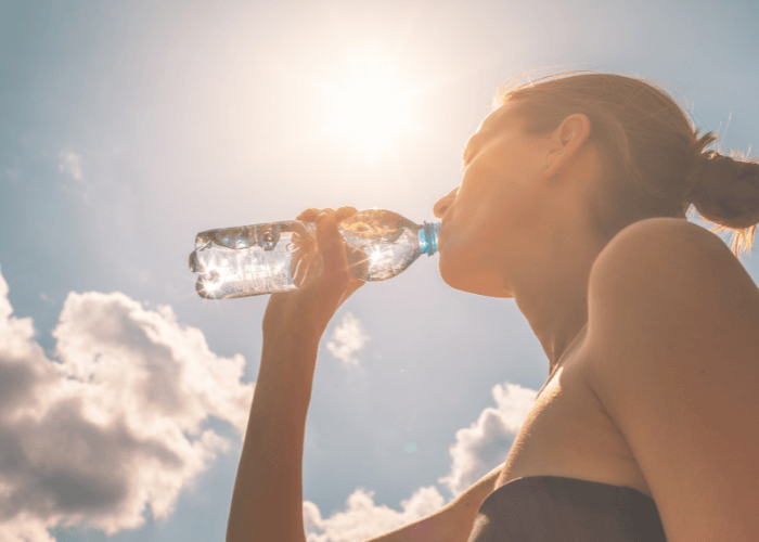 Girl drinking out of a water bottle in the sun