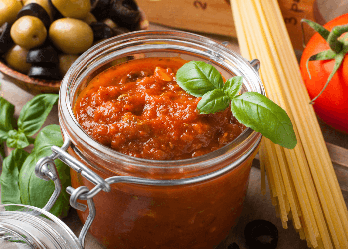 Fresh tomato sauce in a jar with basil leaves and olives