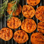 Sliced sweet potatoes on the grill with rosemary