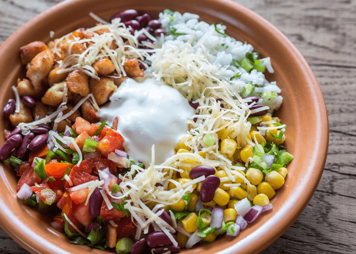 Chipotle Chicken bowl with cheese, guacamole, beans, peppers