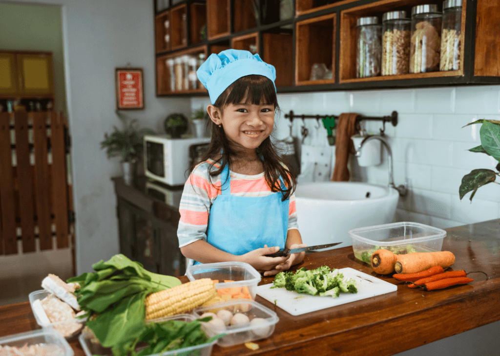 Child in the kitchen using a cutting board for vegetables.