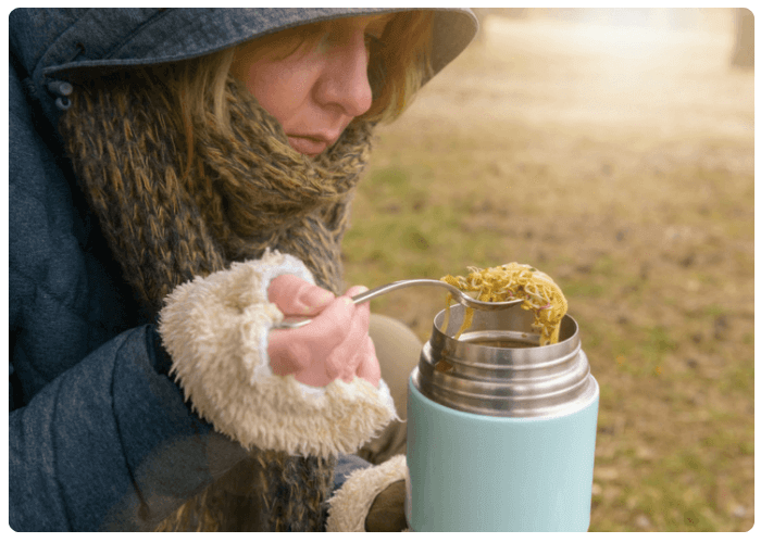 Woman eating from a thermos filled with soup