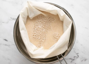 Oat milk in a cheesecloth draining liquid