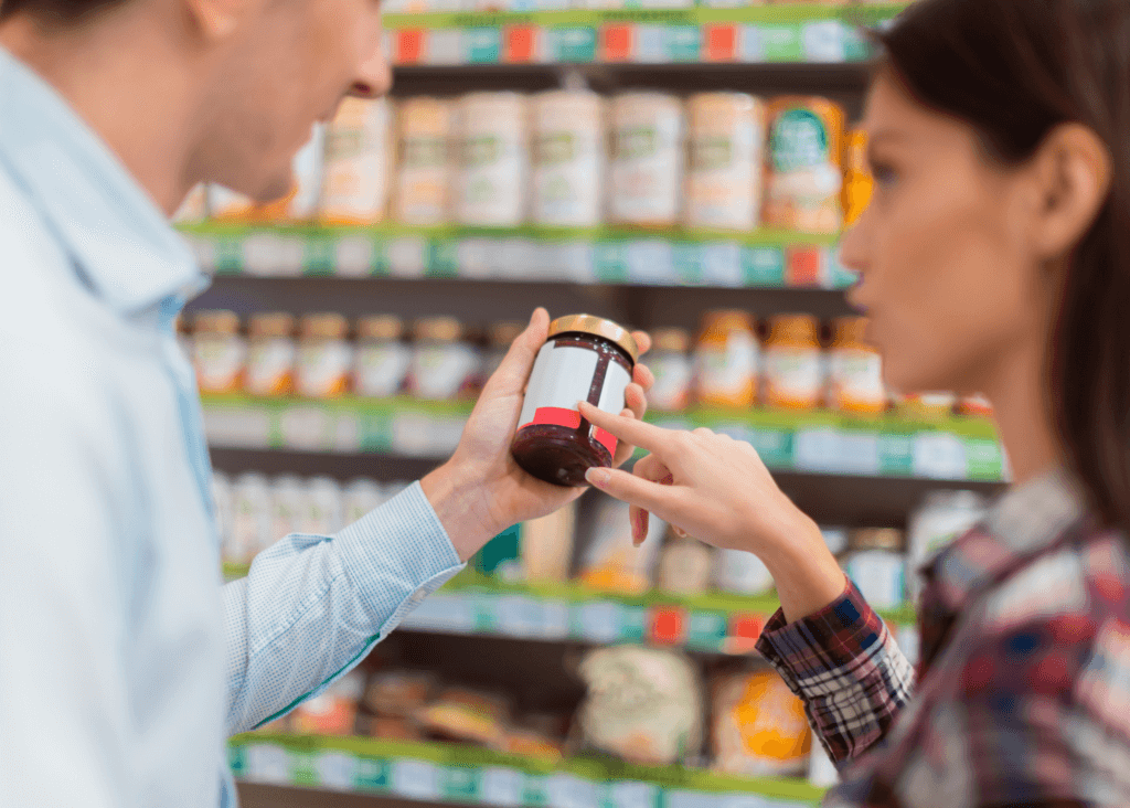 Two people pointing to a nutrition label on a jar of jam