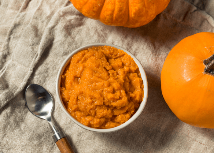 Easy Pumpkin Puree in a white bowl next to a pumpkin