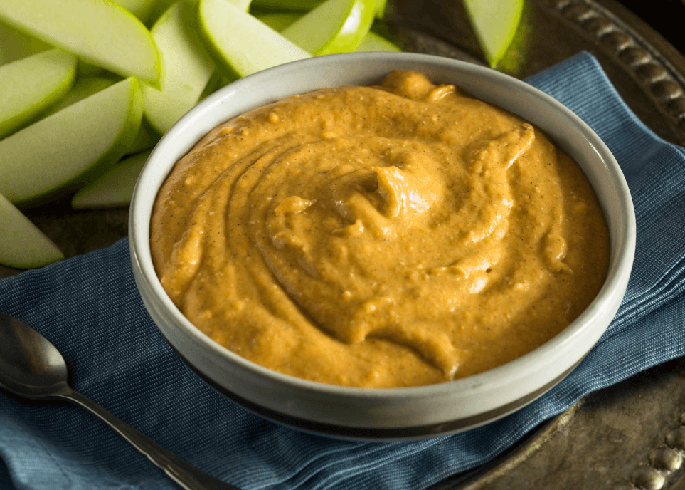 Pumpkin dip in a white bowl with diced apples