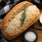 Sourdough Bread loaf with buffalo plaid cloth, bowl of salt, and bowl of starter