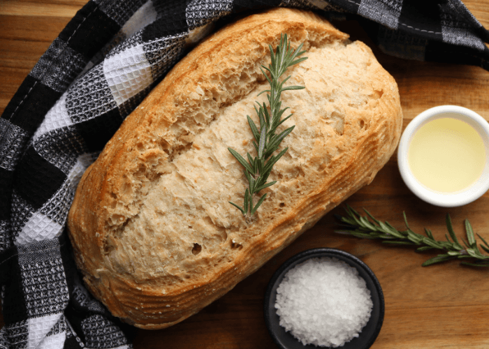 Sourdough Bread loaf with buffalo plaid cloth, bowl of salt, and bowl of starter