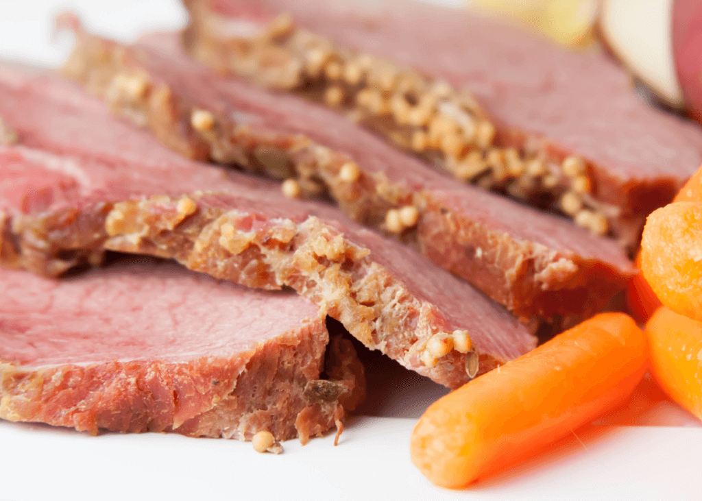 Sliced Buffalo Brisket with cooked carrots on a white plate