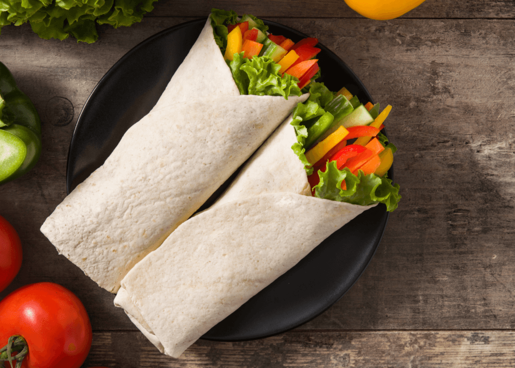 Two tortillas with veggies on a black plate