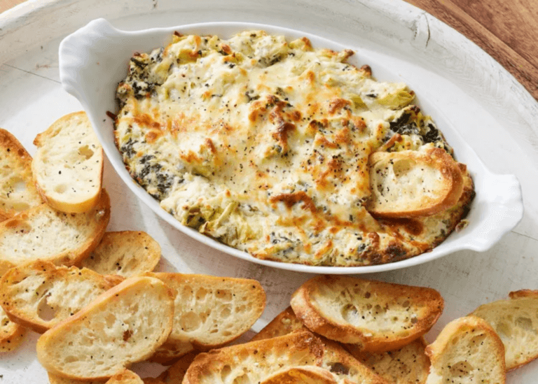 Hot Spinach Artichoke Dip in a white dish with slices of bread