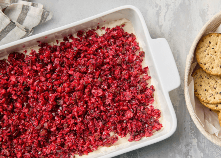 Cranberry Jalapeño Dip in a dish along side a plate of crackers