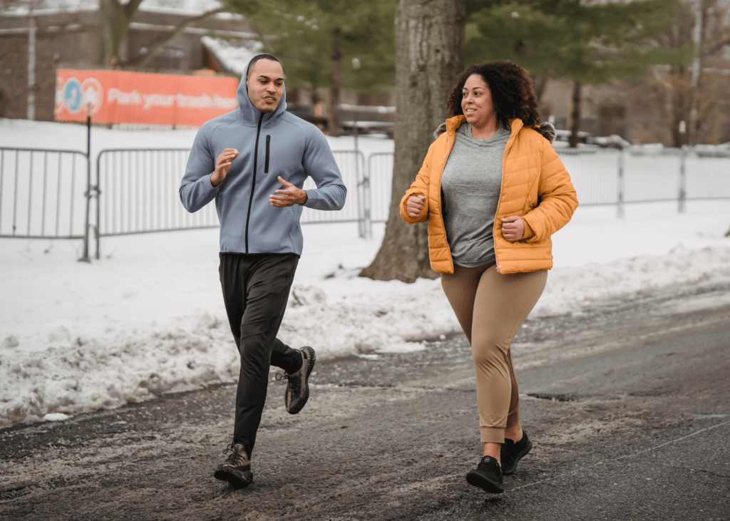 Two people running in the winter on a road