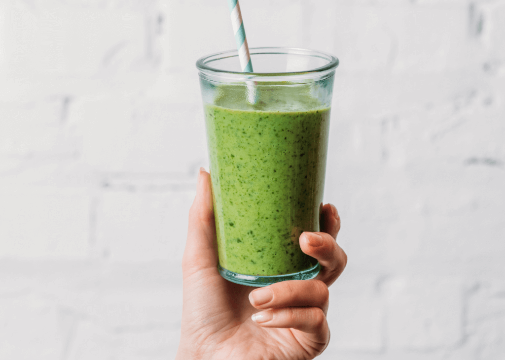 green smoothie glass in a hand