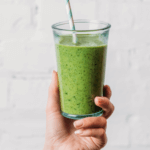 green smoothie glass in a hand