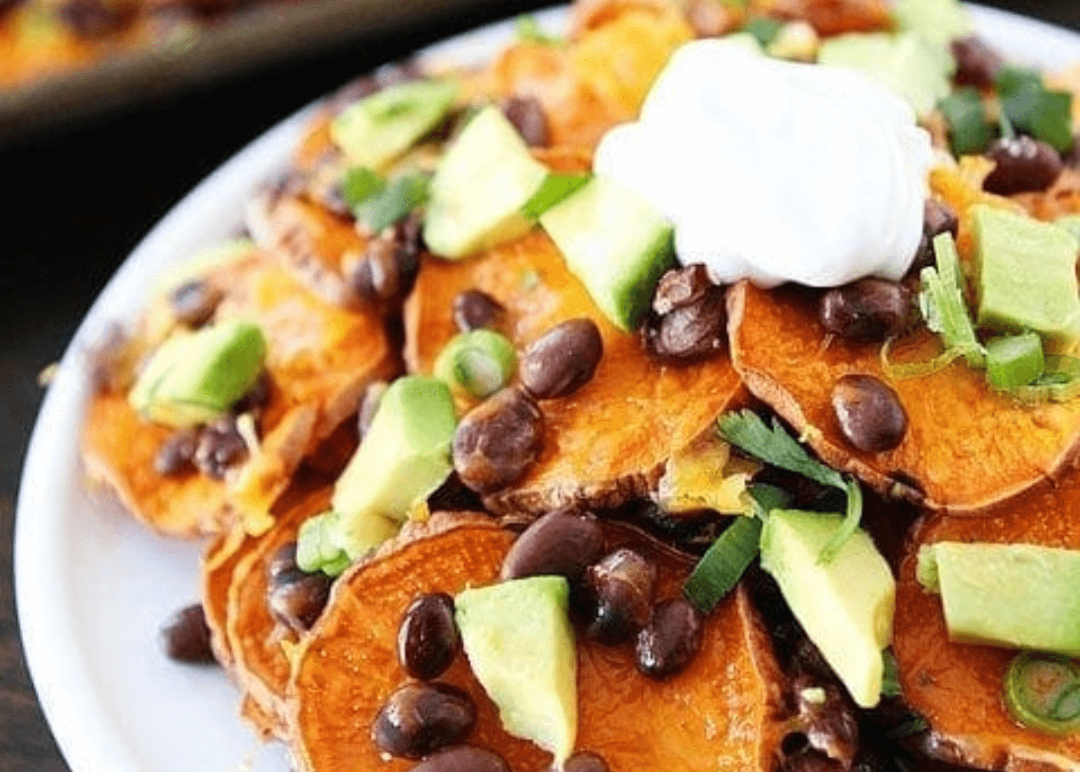 Loaded Sweet Potato Nachos with black beans, sour cream, and chopped avocado