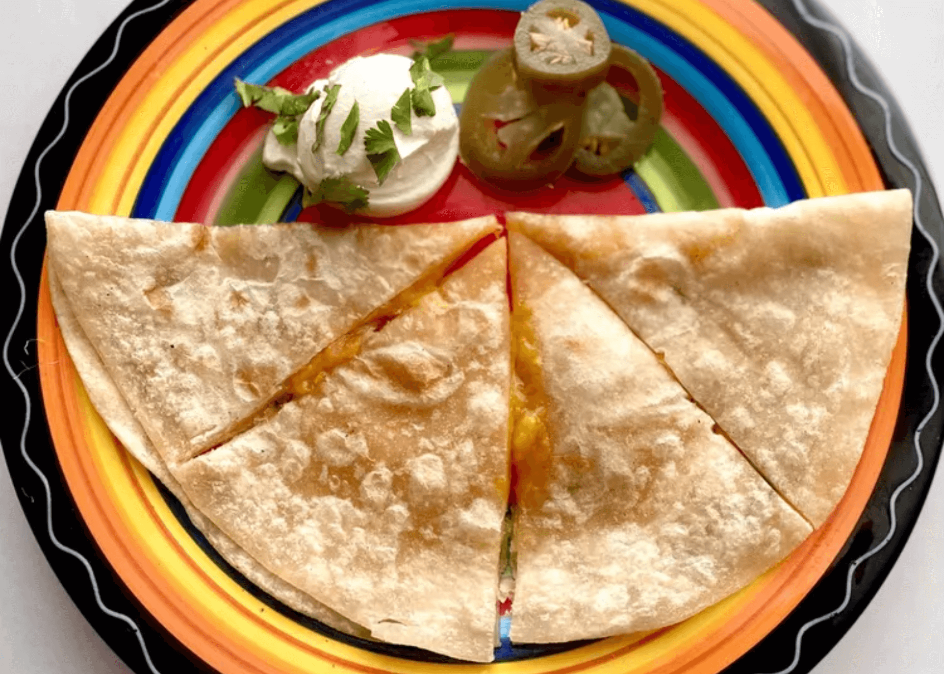 Microwave Quesadilla on a plate with jalapenos and sour cream