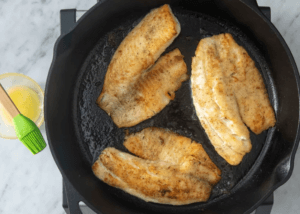 tilapia fillets in a cast iron pan