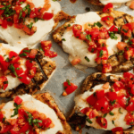 Grilled Bruschetta Chicken breasts with tomatoes and mozzarella on a baking sheet