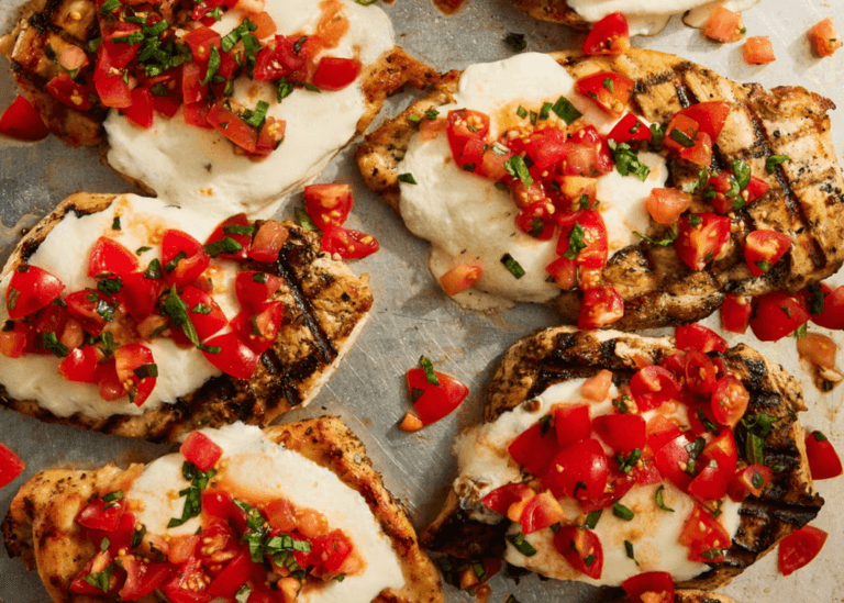 Grilled Bruschetta Chicken breasts with tomatoes and mozzarella on a baking sheet